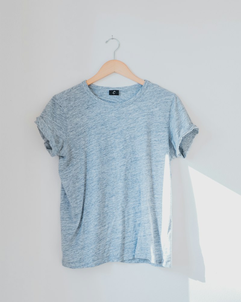 A grey t-shirt hanging against a plain wall